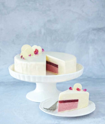 Raspberry and white chocolate entrement on cake stand and slice of cake on plate